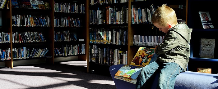 Imagem de um menino numa biblioteca